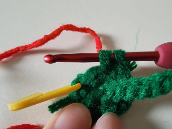 Place the red yarn behind the two loops