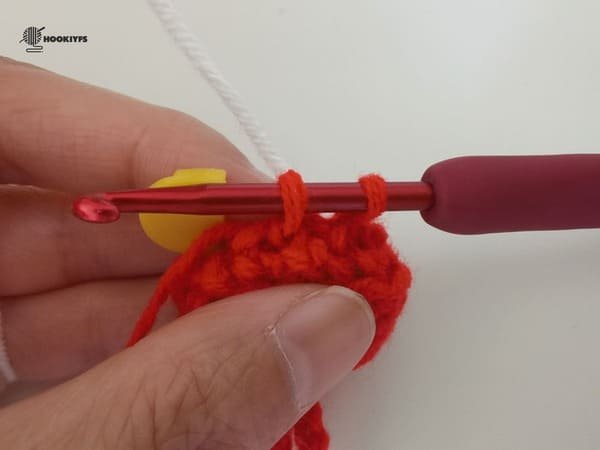 put the white yarn behind two red loops for the last stitch