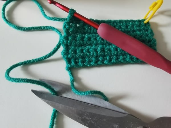 use scissor to cut yarn end for frog crochet pattern